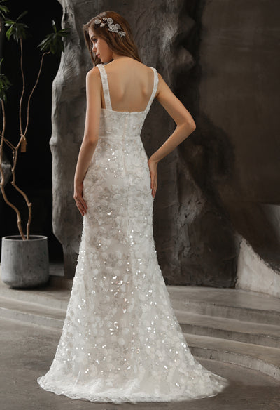 A woman in a Bergamot Bridal Sequined Lace Square Neckline Sheath Wedding Dress with a low back stands in a sophisticated setting.