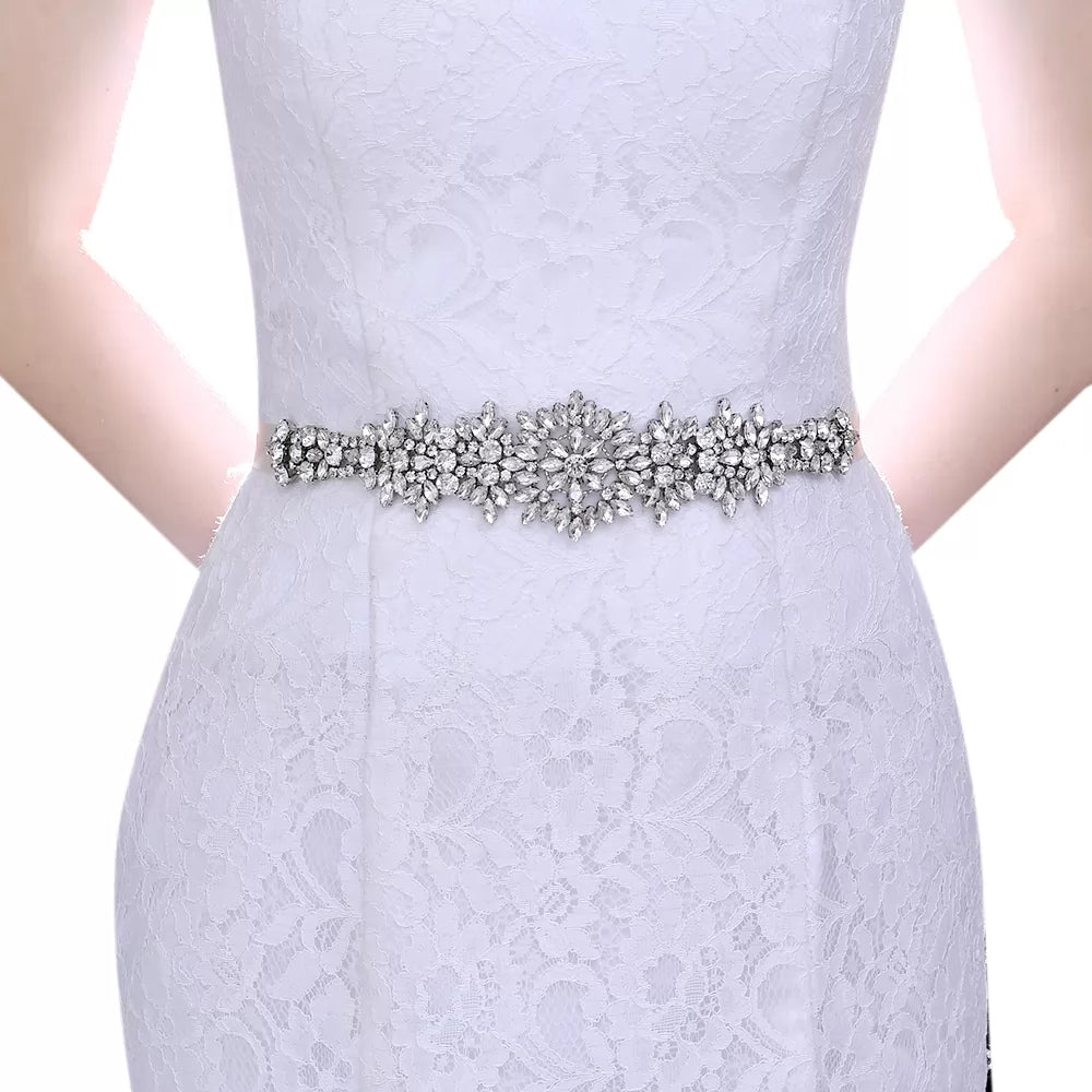 A woman wearing a white lace dress with the Princess Crystals Shimmering Bridal Belt found in Bergamot Bridal.