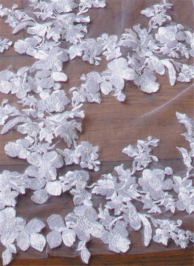 White Floral Lace Cathedral Veil, reminiscent of those found in Bergamot Bridal shops London Ontario, is displayed against a dark wooden background.