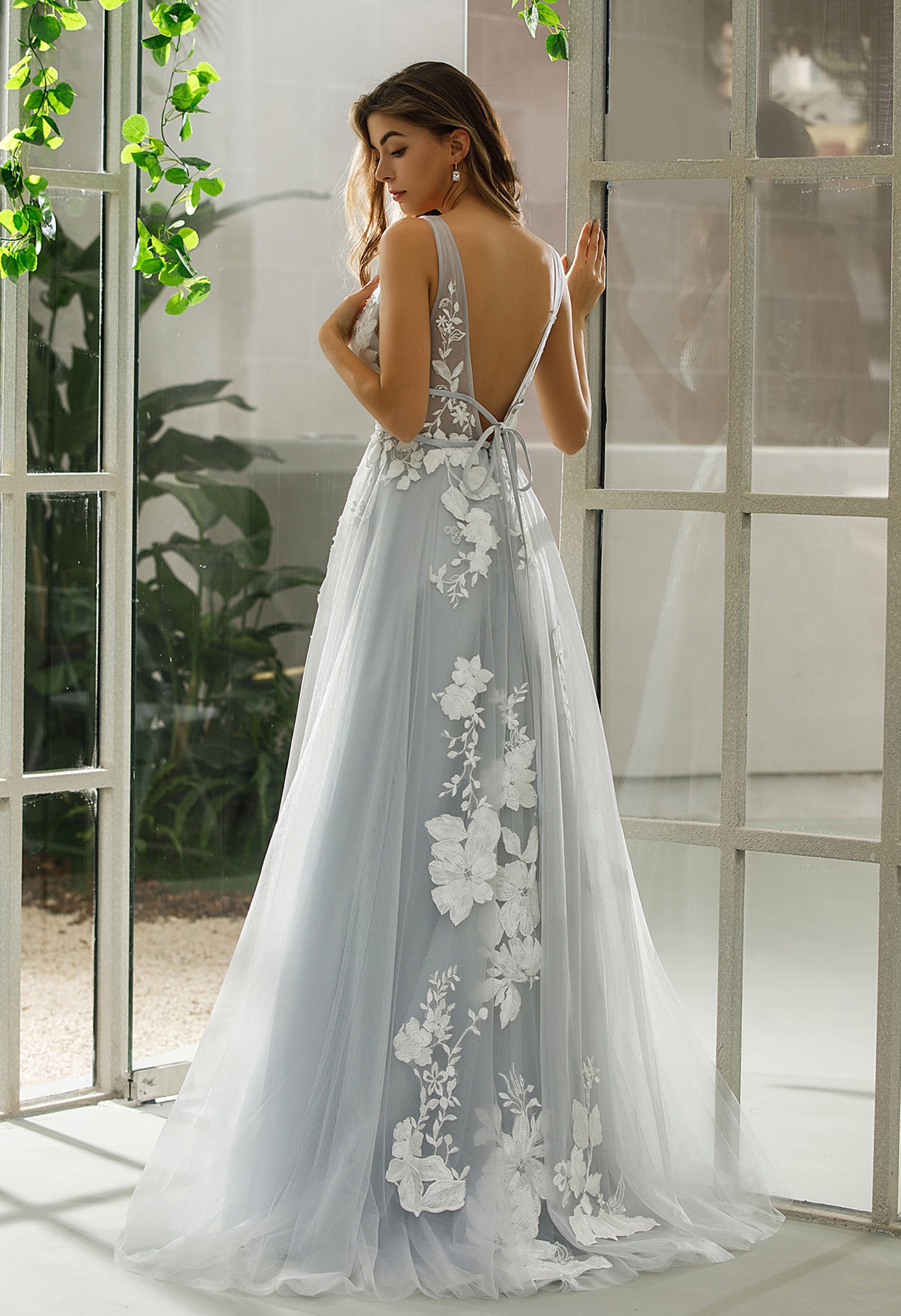 The back view of a woman in a Bergamot Bridal Plunging V-Neck A-Line Ball Gown Bridal Gown at a bridal shop in London.