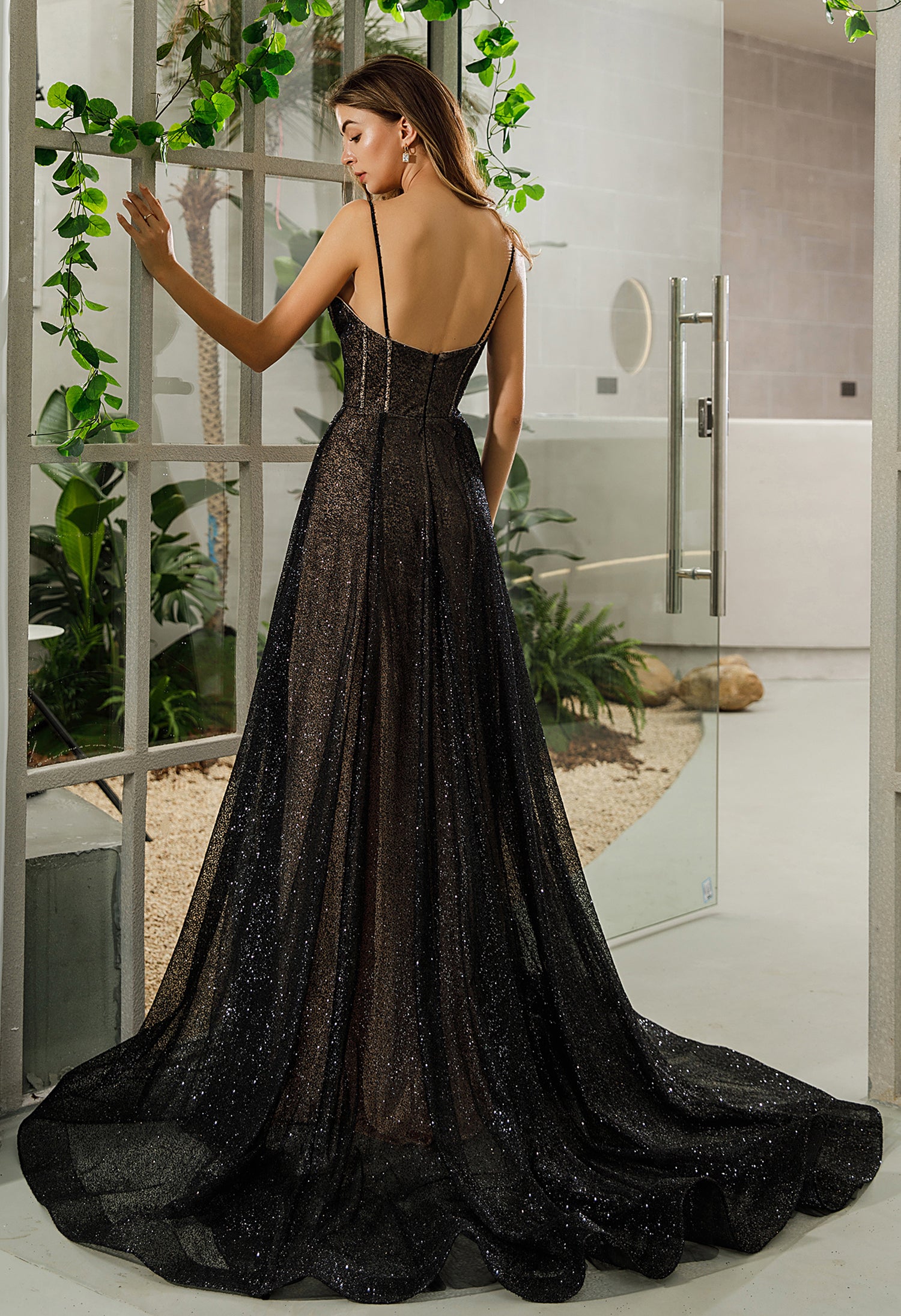 A woman in a Visible Boning Corset Black A-Line Bridal Gown from Bergamot Bridal is standing in front of a window at a bridal shop.
