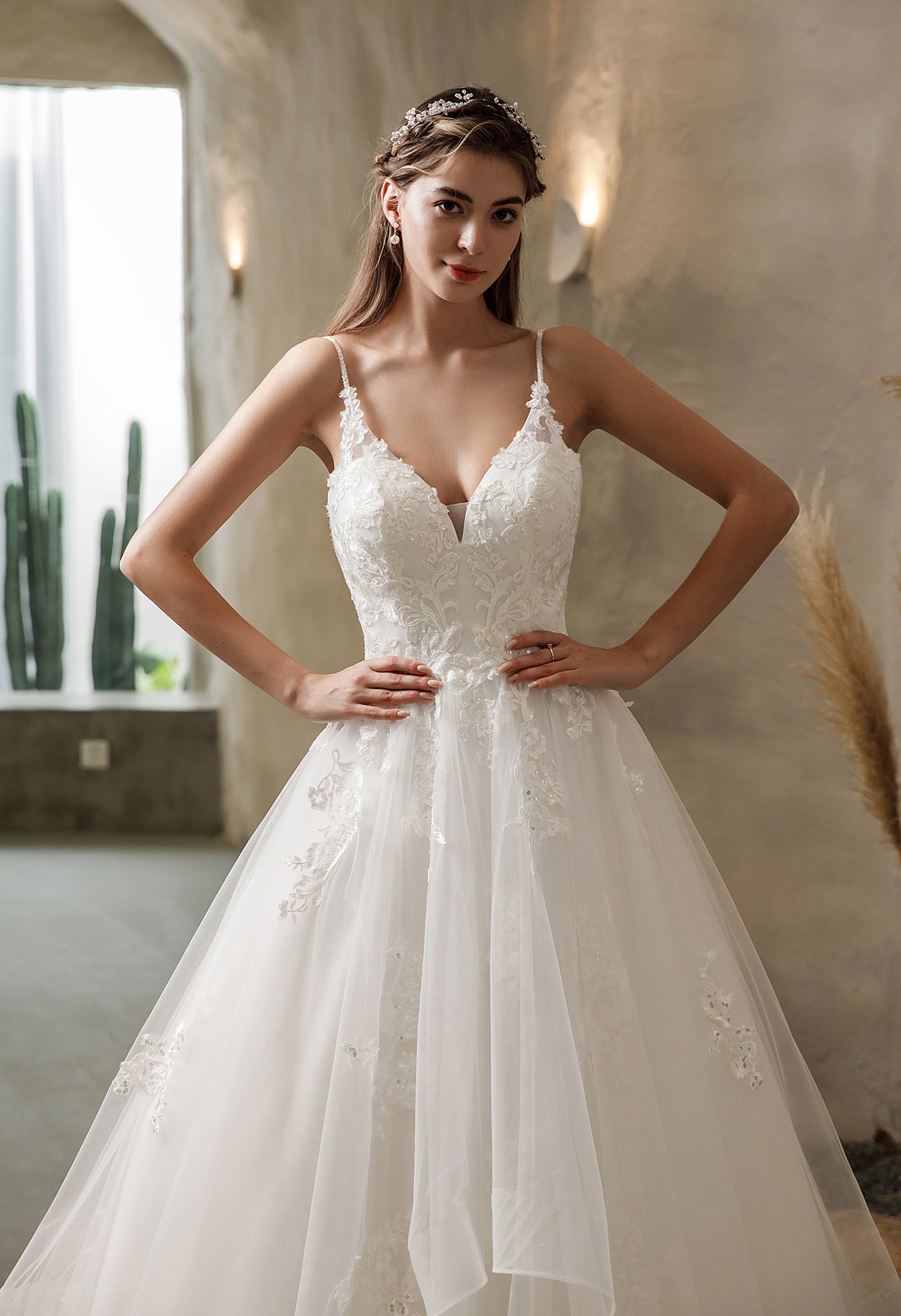 A bride in a white wedding dress is posing in a Bergamot Bridal's Illusion Back Tiered Tulle Skirt Ballgown Bridal Gown - Off The Rack at the bridal shop.