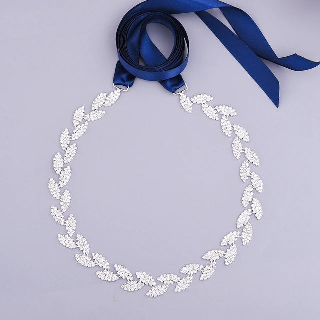 A Silver leaf crystal bridal belt sash with a blue ribbon and rhinestones can be found at Bergamot Bridal shops.