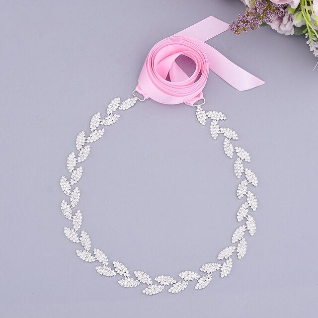 A Silver leaf crystal bridal belt sash with a pink bow on it is commonly found at Bergamot Bridal.