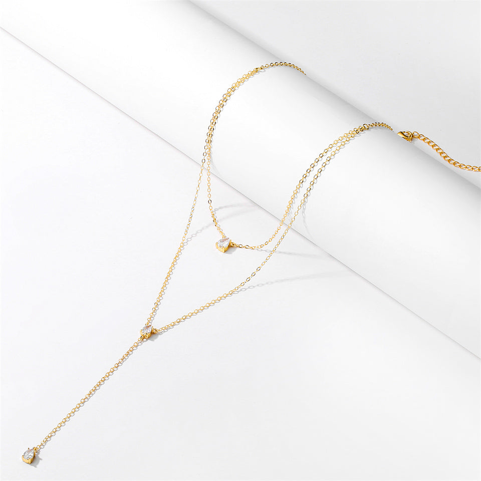 A Bergamot Bridal double layer crystal necklace in gold with small diamonds, displayed elegantly on a white surface, perfect for bridal shops.