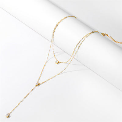 A Bergamot Bridal double layer crystal necklace in gold with small diamonds, displayed elegantly on a white surface, perfect for bridal shops.