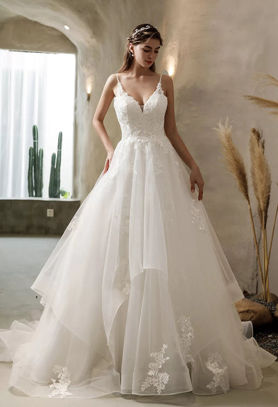 A woman in a white wedding dress is standing in the Bergamot Bridal bridal shop, wearing the Illusion Back Tiered Tulle Skirt Ballgown Bridal Gown - Off The Rack.