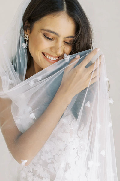 A stunning bride wearing a white wedding dress adorned with a Bergamot Bridal 3d Floral Cathedral Wedding Veil.